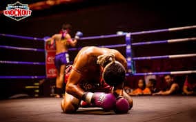 Combattant à genoux dans le ring après l'effort, mongkhon sur la tête